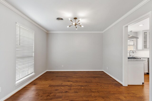 spare room featuring baseboards, ornamental molding, wood finished floors, and a chandelier