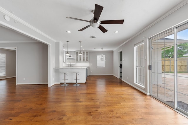 unfurnished living room with crown molding, recessed lighting, baseboards, and wood finished floors