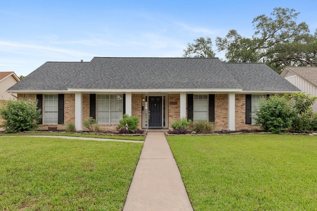 ranch-style home with roof with shingles, a front yard, and brick siding