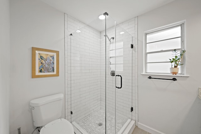 bathroom featuring baseboards, toilet, and a shower stall