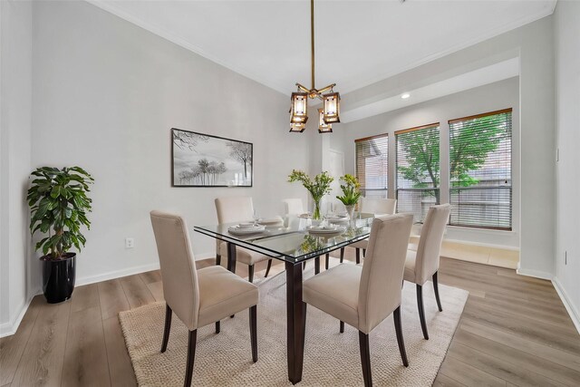 dining room with light wood-style floors, baseboards, ornamental molding, and a notable chandelier