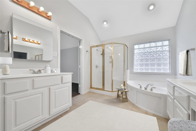 bathroom featuring tile patterned flooring, a bath, two vanities, a stall shower, and vaulted ceiling