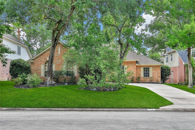 obstructed view of property with brick siding, driveway, roof with shingles, and a front lawn