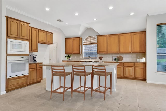 kitchen featuring brown cabinetry, recessed lighting, backsplash, and white appliances