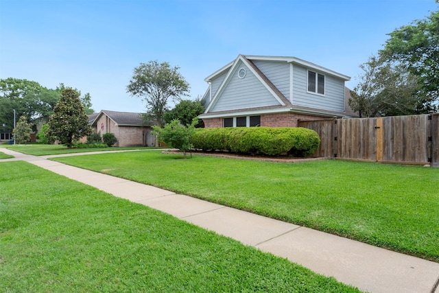 view of property exterior featuring fence, a yard, and brick siding