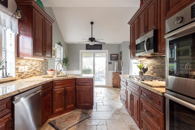 kitchen featuring a sink, stainless steel appliances, lofted ceiling, backsplash, and stone tile flooring