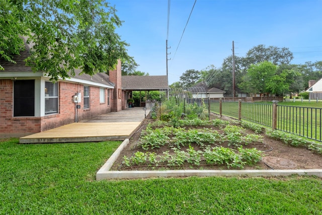 view of yard with fence, a vegetable garden, and a deck