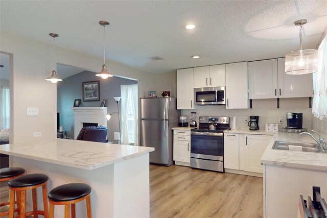 kitchen featuring a sink, light wood-style floors, stainless steel appliances, and white cabinetry