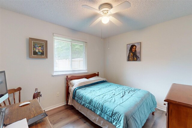 bedroom featuring a textured ceiling, baseboards, and wood finished floors