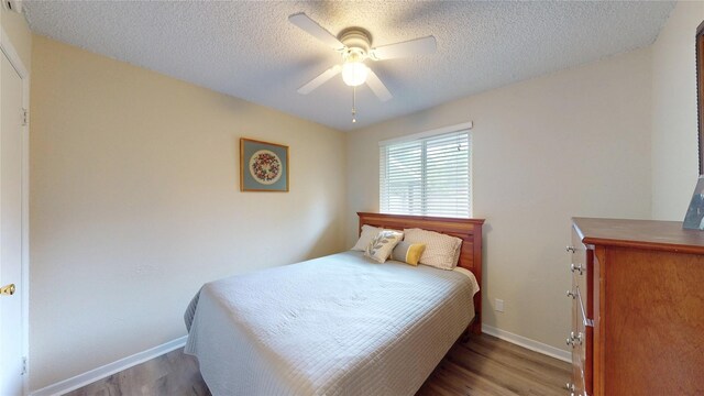 bedroom featuring baseboards, a ceiling fan, a textured ceiling, and wood finished floors