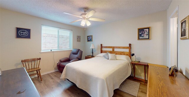 bedroom featuring baseboards, a ceiling fan, a textured ceiling, and wood finished floors