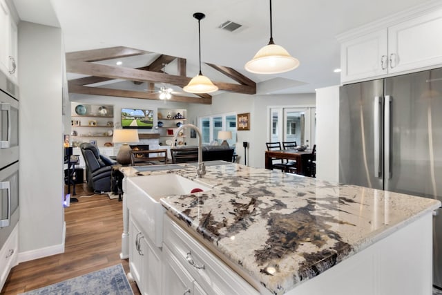 kitchen with a sink, white cabinets, freestanding refrigerator, open floor plan, and dark wood-type flooring