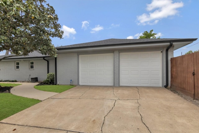garage featuring fence, central AC unit, and driveway