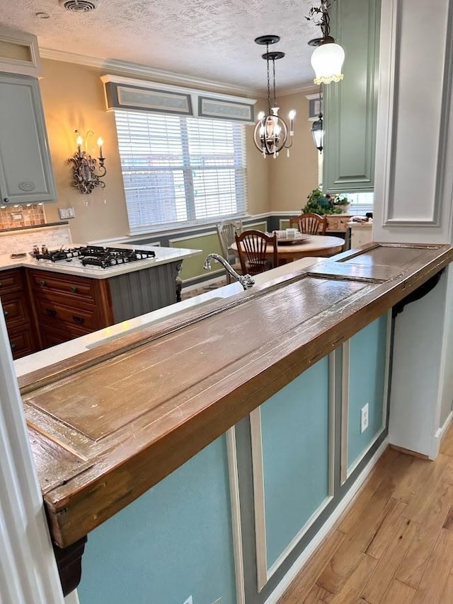 18606 Spring Heather Ct, Spring, TX 77379 - kitchen with ornamental molding, light wood-type flooring, a textured ceiling, pendant lighting, and white gas stovetop