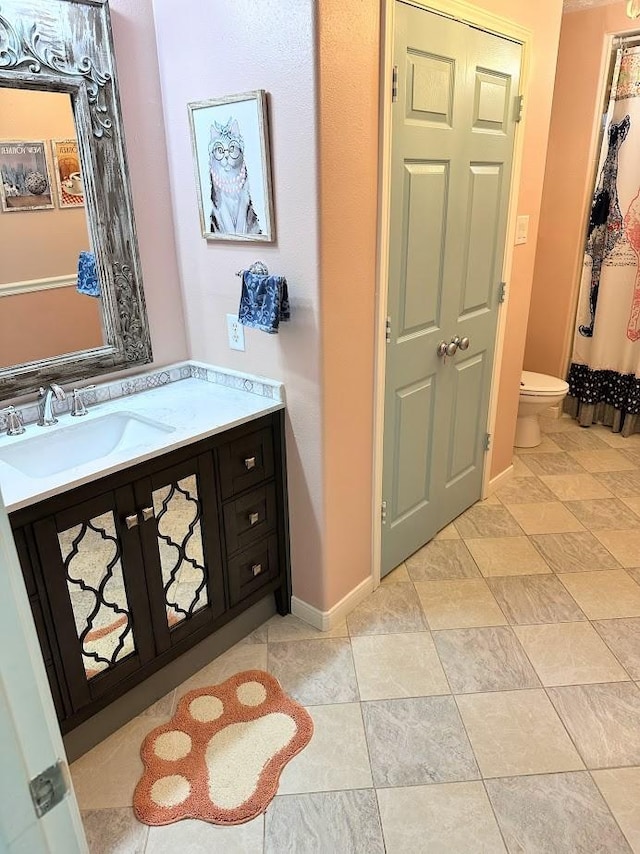 full bathroom featuring toilet, baseboards, and vanity