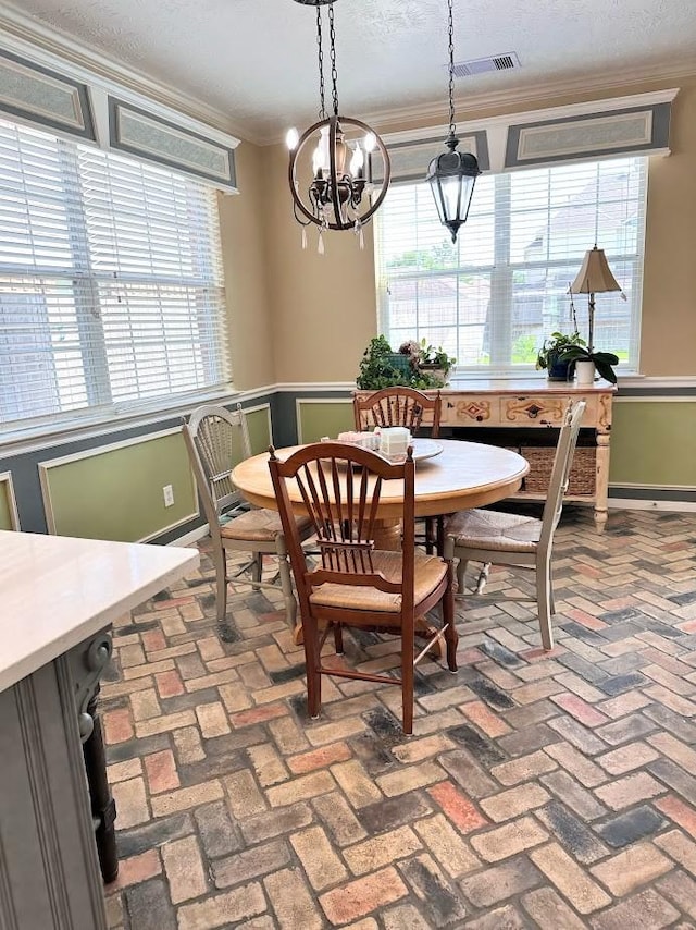 dining room featuring crown molding, brick floor, a notable chandelier, and visible vents