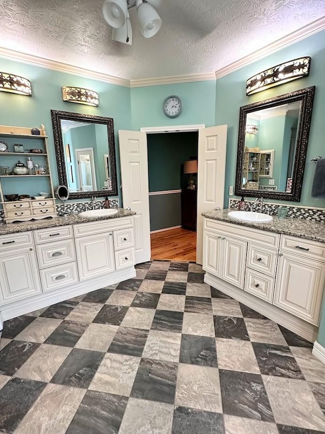 bathroom featuring vanity, ornamental molding, and a textured ceiling