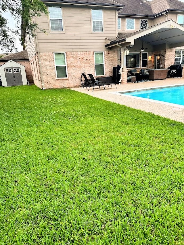 back of property with an outdoor living space, a lawn, an outbuilding, brick siding, and a shed
