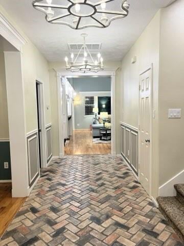 18606 Spring Heather Ct, Spring, TX 77379 - corridor featuring a chandelier, brick flooring, and stairs