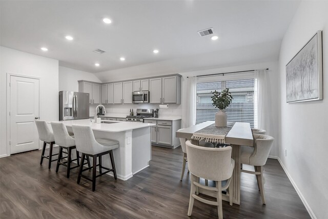 kitchen with visible vents, a kitchen island with sink, a sink, appliances with stainless steel finishes, and gray cabinetry