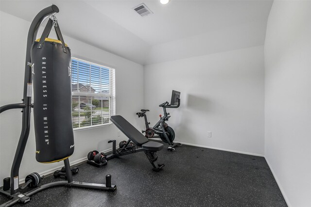 exercise room with baseboards, vaulted ceiling, and visible vents