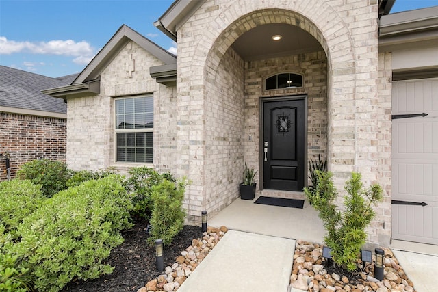 entrance to property with brick siding and a garage