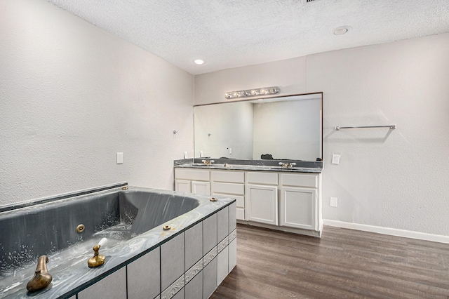 16226 Alden Ridge Dr, Houston, TX 77053 - bathroom with double vanity, a textured ceiling, a jetted tub, baseboards, and wood finished floors