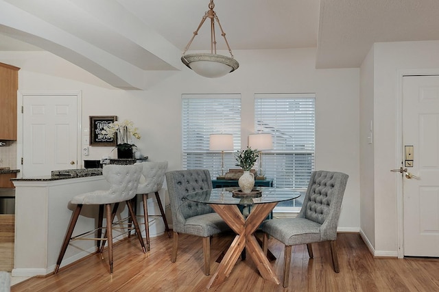 dining area with baseboards, arched walkways, and wood finished floors
