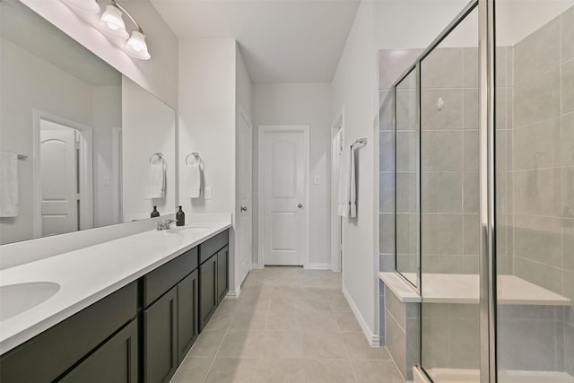 full bathroom featuring double vanity, a shower stall, a sink, and tile patterned flooring