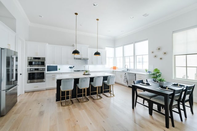 kitchen with a breakfast bar area, appliances with stainless steel finishes, a wealth of natural light, and a sink
