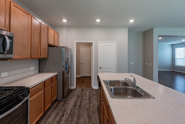 kitchen with a sink, light countertops, stainless steel appliances, baseboards, and dark wood-type flooring