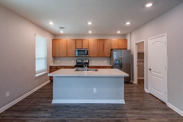 kitchen with baseboards, light countertops, appliances with stainless steel finishes, and an island with sink