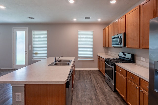kitchen with appliances with stainless steel finishes, a sink, baseboards, visible vents, and dark wood-style floors
