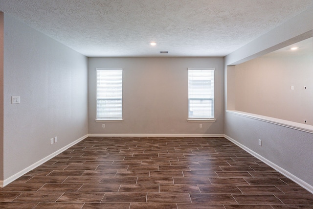 unfurnished room with baseboards, a textured ceiling, dark wood-style flooring, and visible vents