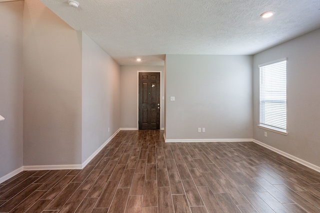 empty room featuring recessed lighting, baseboards, dark wood-style flooring, and a textured ceiling