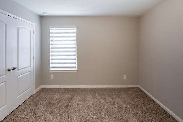 empty room featuring baseboards and carpet flooring