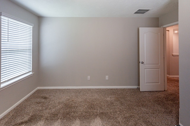 unfurnished room featuring baseboards, visible vents, and carpet