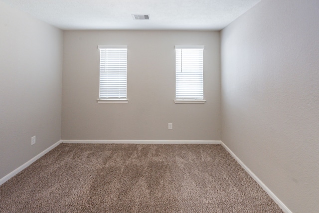 carpeted spare room featuring baseboards and visible vents