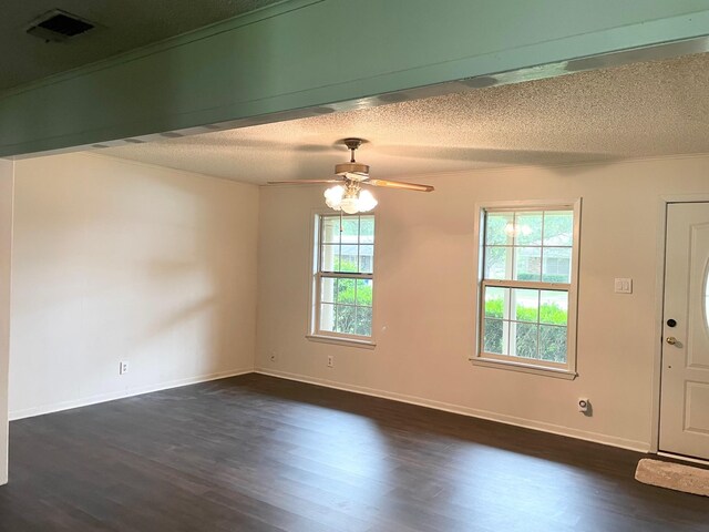 empty room featuring a textured ceiling, ceiling fan, dark wood finished floors, and baseboards