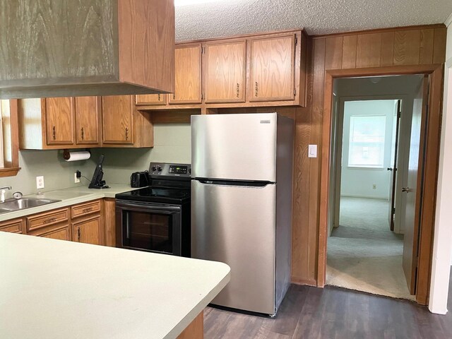 kitchen featuring a sink, light countertops, freestanding refrigerator, dark wood-type flooring, and black range with electric cooktop