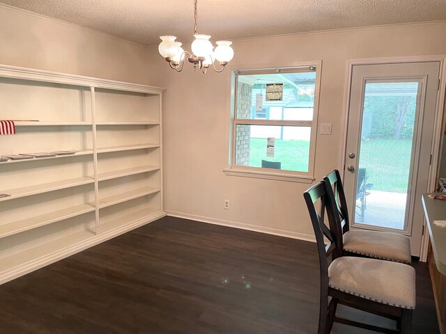 unfurnished dining area with ornamental molding, baseboards, a textured ceiling, dark wood finished floors, and a notable chandelier
