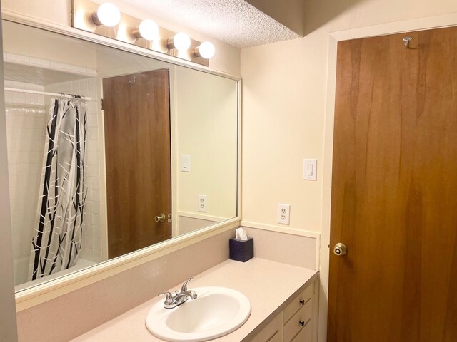 full bath with a textured ceiling and vanity