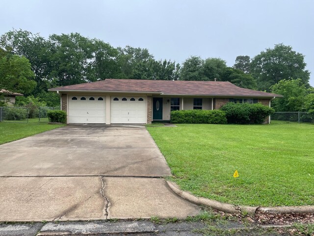 single story home featuring an attached garage, brick siding, fence, and a front yard