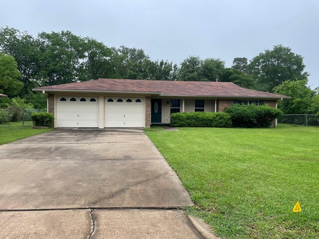 ranch-style home featuring a garage, fence, concrete driveway, and a front lawn