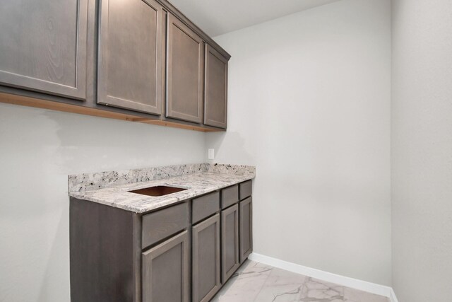 laundry area with baseboards and marble finish floor