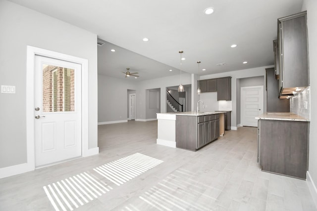 kitchen featuring a kitchen island with sink, open floor plan, and baseboards