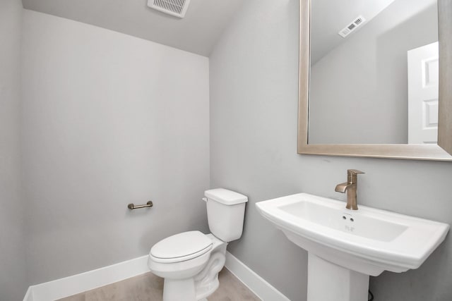 bathroom featuring toilet, baseboards, visible vents, and a sink