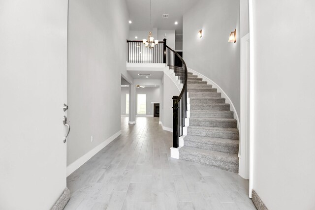foyer featuring baseboards, a high ceiling, stairway, recessed lighting, and a notable chandelier