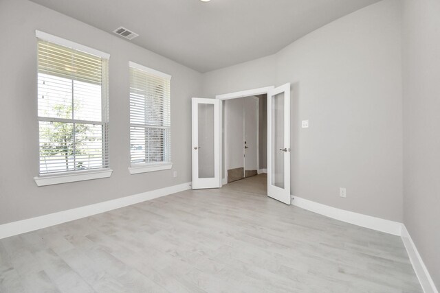 spare room featuring visible vents, baseboards, light wood finished floors, and french doors