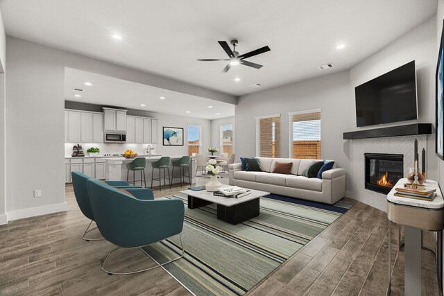 living area featuring visible vents, light wood-style flooring, ceiling fan, and a fireplace